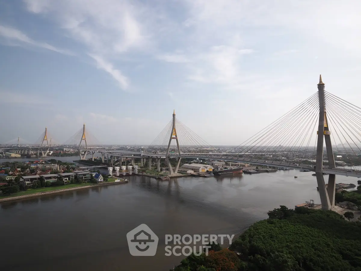Stunning aerial view of a modern cable-stayed bridge over a serene river, showcasing urban landscape and architectural marvel.