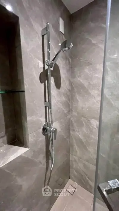 Modern bathroom with sleek marble shower design and chrome fixtures.
