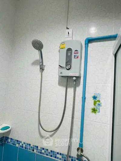 Modern bathroom with electric shower and tiled walls, featuring blue accents.