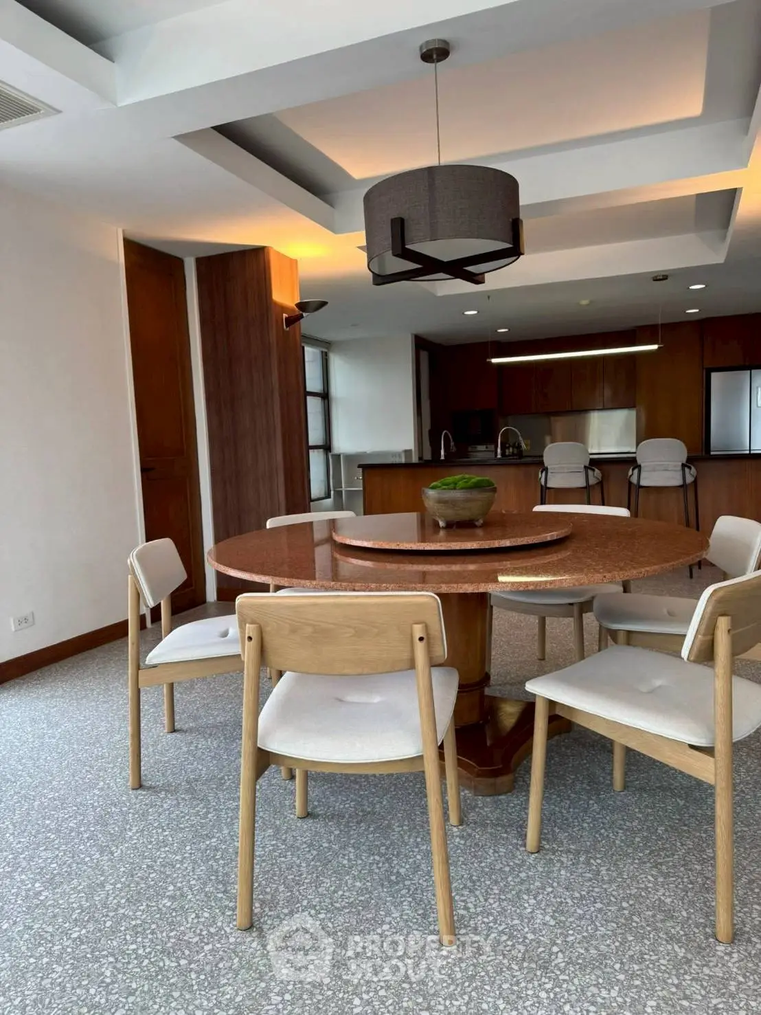 Spacious dining area with modern lighting and open kitchen layout, perfect for entertaining guests.