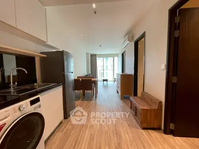 Modern apartment interior with kitchen and living area, featuring wooden flooring and natural light.