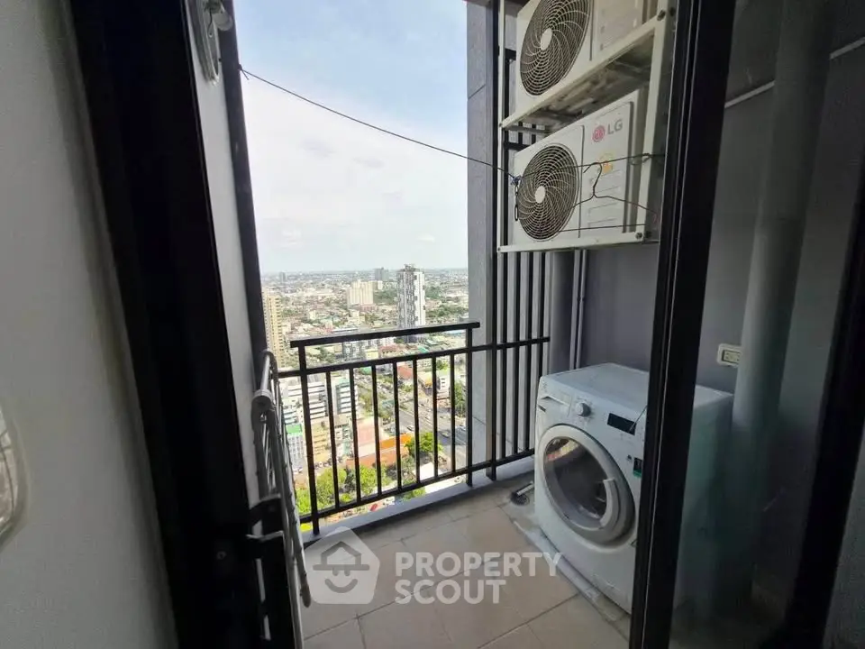 High-rise balcony with city view, featuring washing machine and air conditioning units.