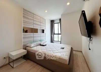 Modern bedroom with stylish decor and large window offering natural light.