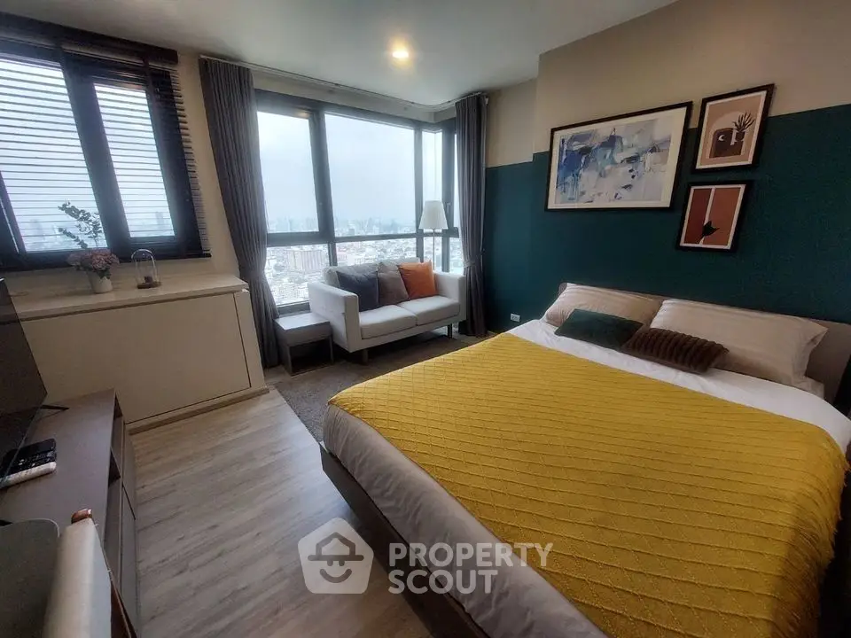 Modern bedroom with city view, stylish decor, and cozy seating area.