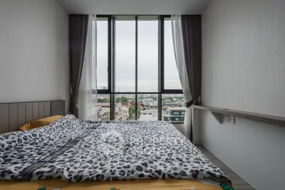 Modern bedroom with large window offering stunning city view and stylish decor.