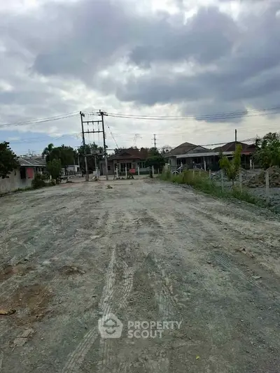 Vacant land plot with potential for development under cloudy skies.
