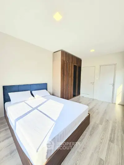 Bright and spacious bedroom with modern wooden wardrobe and stylish bed.
