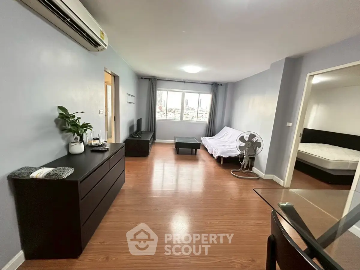 Spacious living room with modern furniture and wooden flooring in a cozy apartment.