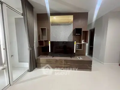 Modern living room with sleek TV unit and air conditioning, featuring elegant design and ample storage.