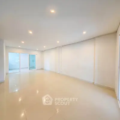 Spacious empty living room with bright lighting and tiled flooring, perfect for customization.