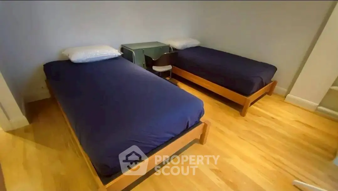 Spacious bedroom with twin beds and wooden flooring for cozy living.