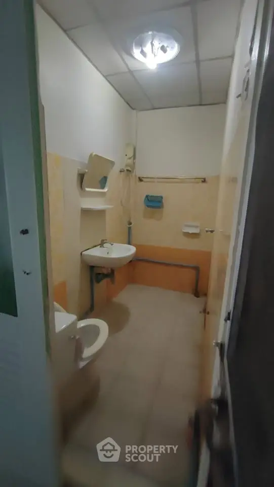 Compact bathroom with essential fixtures and tiled walls, ideal for efficient space utilization.
