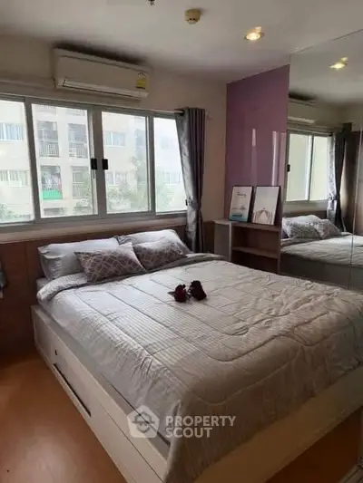Cozy bedroom with large windows and mirrored closet in modern apartment.