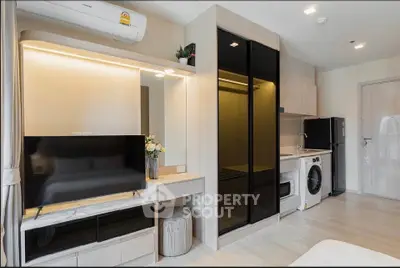 Modern studio apartment with sleek design, featuring a compact kitchen, washing machine, and stylish TV setup.