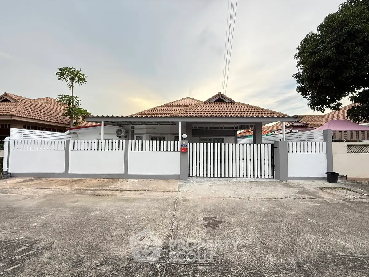 Charming single-story house with a tiled roof and gated front yard in a serene neighborhood.