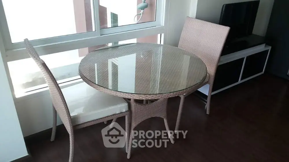 Chic modern living room with glass-top table and wicker chairs, perfect for cozy gatherings.