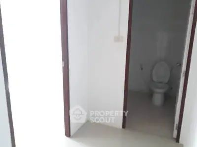 Simple bathroom with white walls and toilet in a minimalistic design.