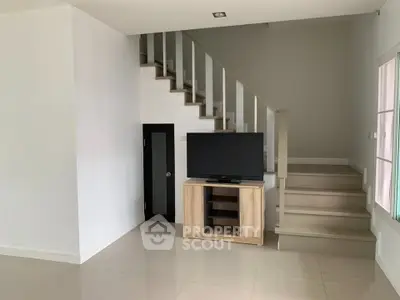 Modern living room with sleek staircase and TV stand, perfect for stylish urban living.