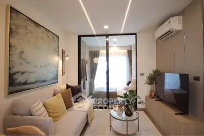 Modern living room with cozy decor and large artwork, featuring a view into a stylish bedroom.