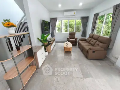 Spacious living room with modern furniture and large windows offering garden views.