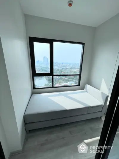 Bright and airy corner unit with a built-in daybed, showcasing a panoramic city view through a large picture window, perfect for urban living.