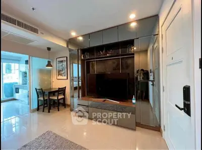 Modern living room with sleek TV unit and dining area in open layout apartment.