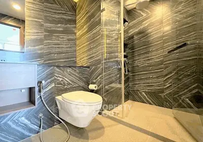 Luxurious modern bathroom with sleek marble walls and glass shower enclosure.