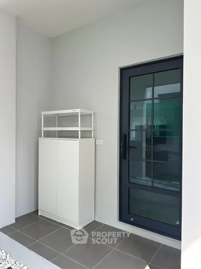 Modern entrance with sleek glass door and minimalist white storage cabinet