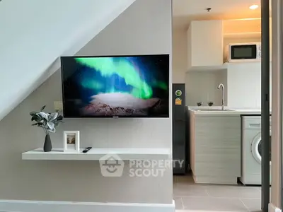 Modern living space with TV, sleek kitchen, and washing machine in compact design.