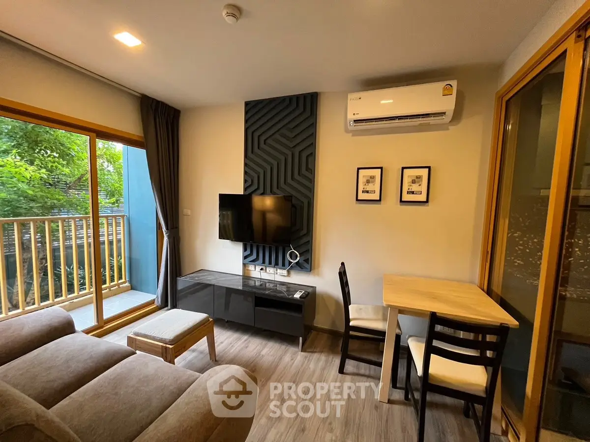 Modern living room with balcony view, featuring sleek furniture and air conditioning.