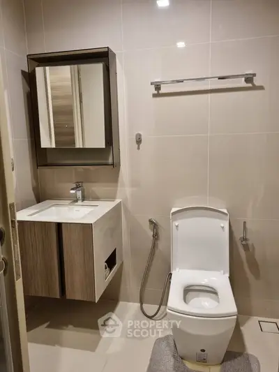 Modern bathroom with sleek fixtures and neutral tones, featuring a stylish vanity and toilet.