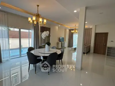 Luxurious open-plan living and dining area with elegant chandelier and pool view.