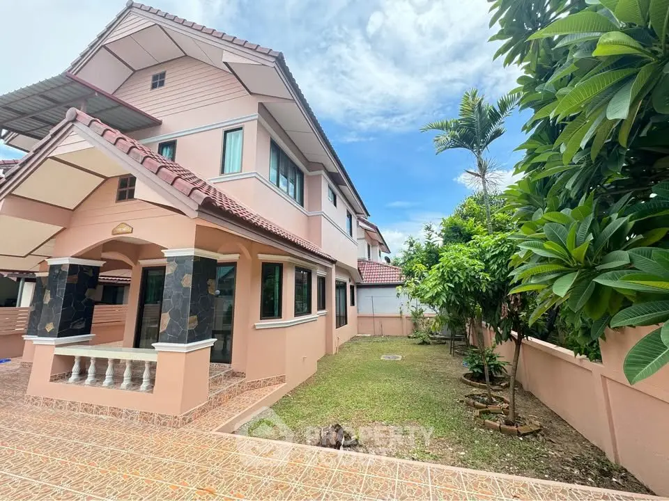 Charming two-story house with tiled roof and lush garden in serene neighborhood.