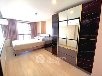 Spacious modern bedroom with large windows and elegant wardrobe in a stylish apartment.