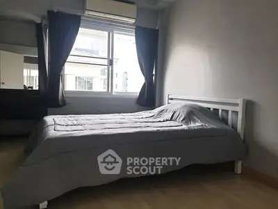 Cozy bedroom with modern decor and large window for natural light.