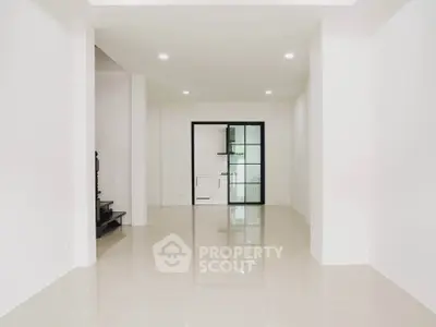 Spacious minimalist interior with glossy tiled floors and modern glass door.