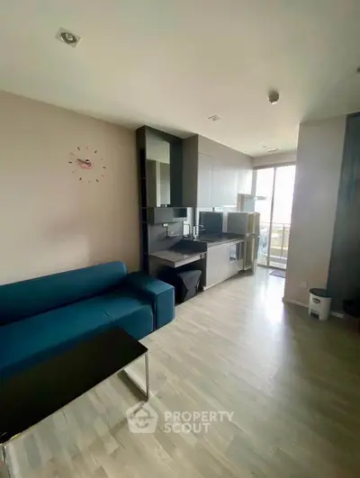 Modern living room with sleek kitchen and balcony access, featuring stylish furniture and contemporary design.