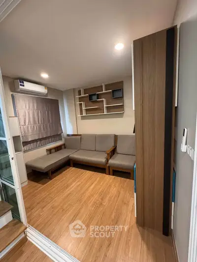 Modern living room with wooden flooring, stylish shelving, and cozy seating area.