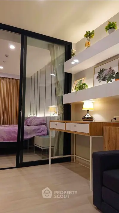 Modern bedroom with stylish decor and sliding glass partition, featuring elegant shelving and warm lighting.