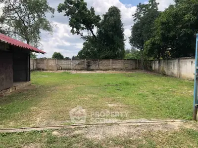 Spacious residential land plot with lush greenery and privacy fence, ideal for building your dream home.