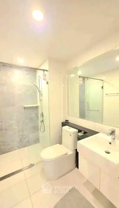 Modern bathroom with glass shower and sleek fixtures in a bright, minimalist design.