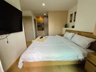 Modern bedroom with cozy wooden furniture and large TV, perfect for relaxation.
