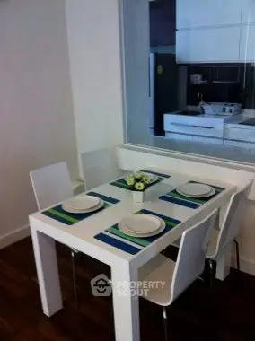 Modern dining area with sleek white table and chairs, set for four, in a contemporary kitchen.