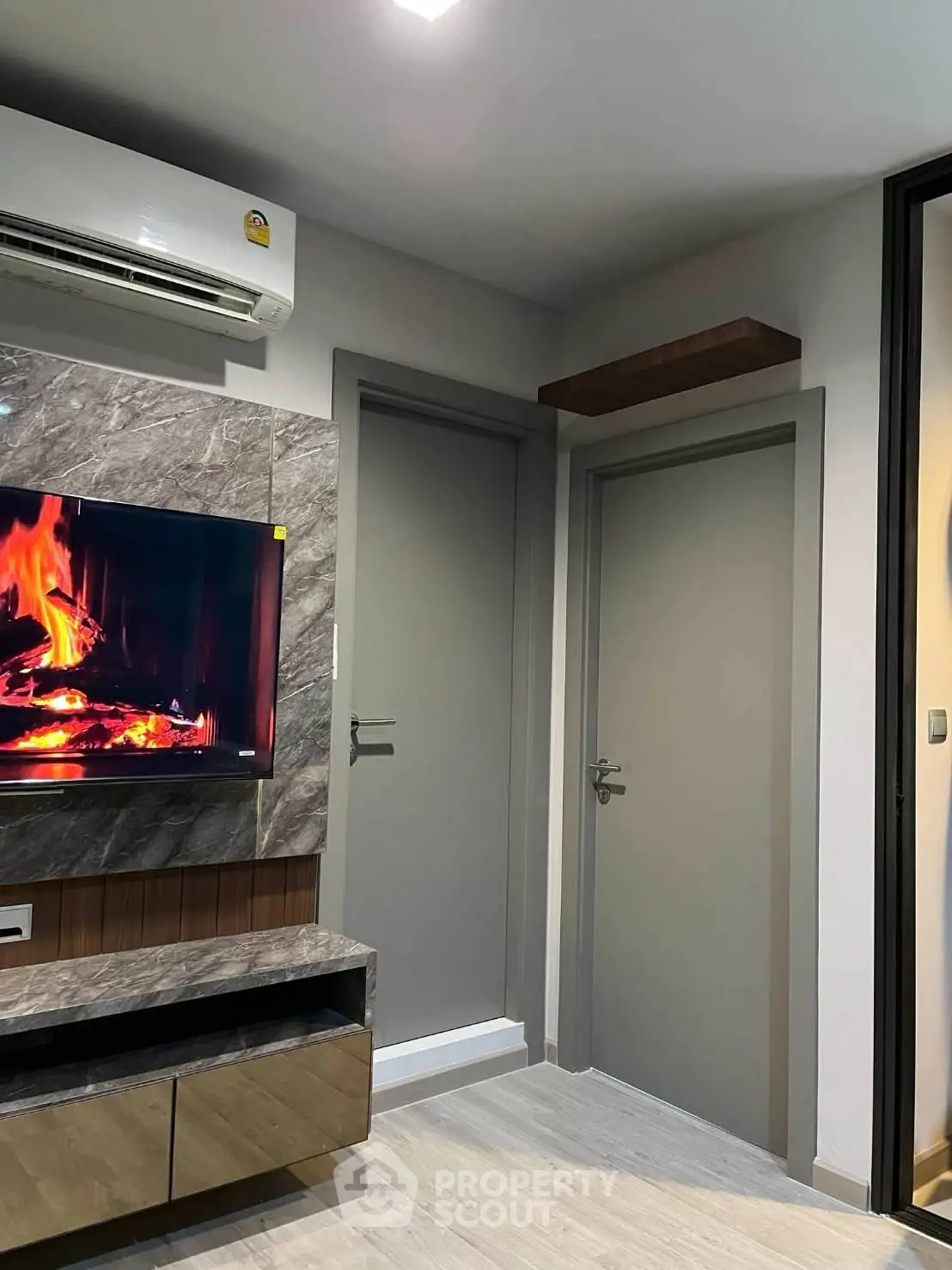 Modern living room with stylish TV setup and air conditioning, featuring elegant wood and marble finishes.