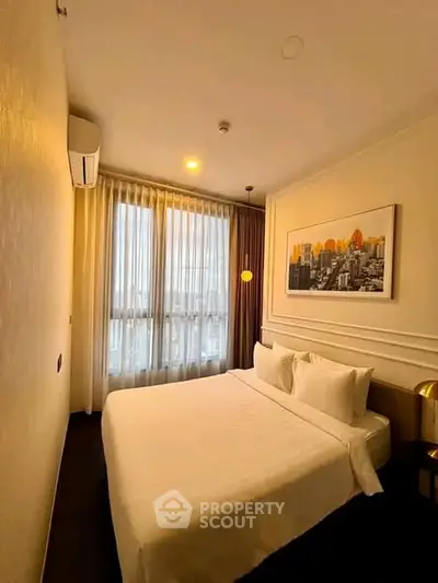 Cozy bedroom with cityscape artwork and large window, perfect for urban living.