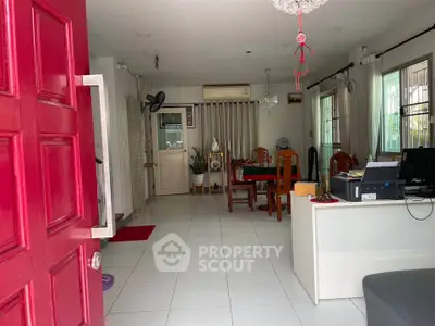 Spacious living room with red door, tiled floor, and elegant decor