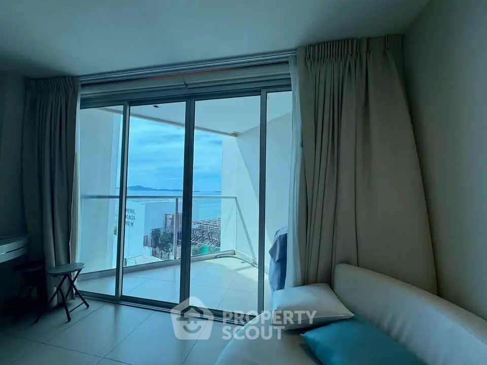 Spacious living room with stunning ocean view from large balcony, perfect for relaxation.