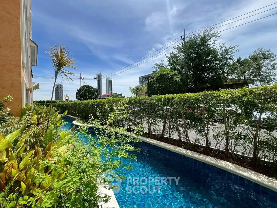 Stunning outdoor pool with lush greenery and cityscape view, perfect for relaxation.