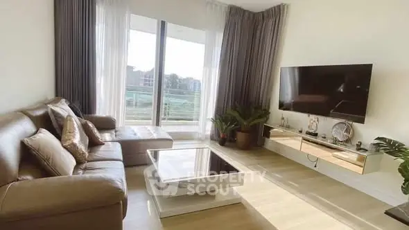 Modern living room with large windows and stylish decor, featuring a sleek TV setup and comfortable seating.