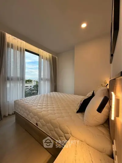 Cozy bedroom with large window and modern decor, perfect for relaxation.